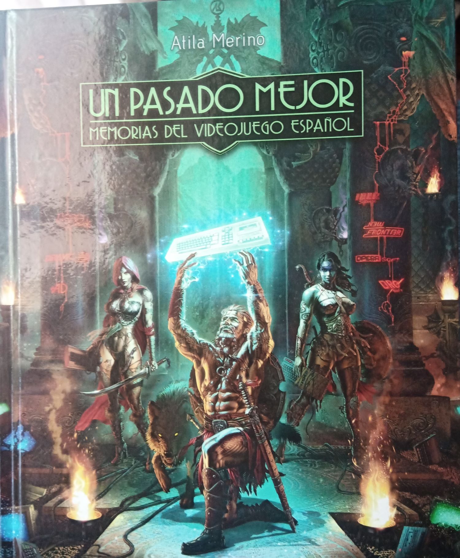 The front cover of Un Pasado Mejor: Memorias del videojuego Español, written by Atila Merino and published by GamePress. The illustration features a buff dude with a sword and shield kneeling on one leg, holding a glistening, glimmering Amstrad CPC above his head. 