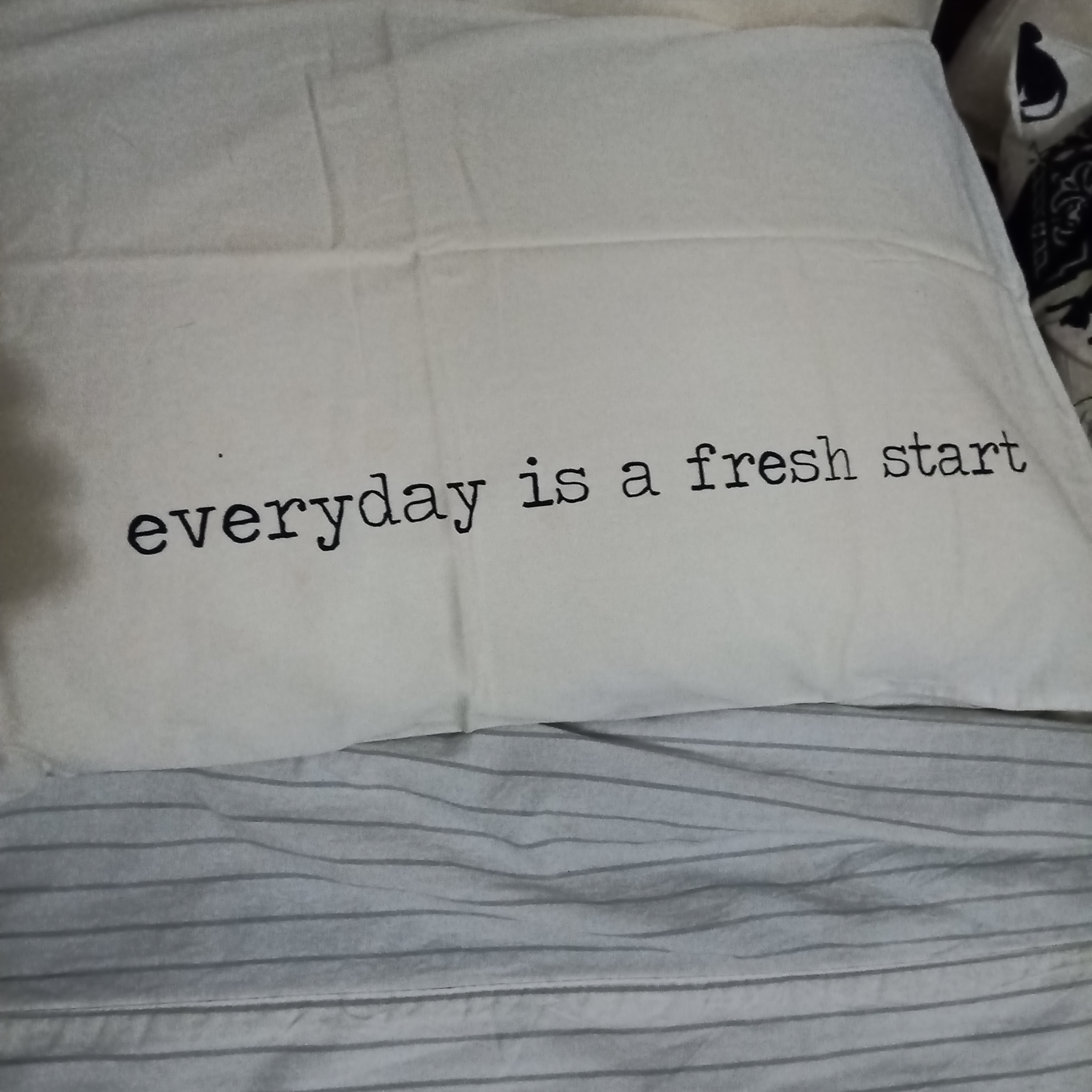 A white pillowcase with the black text "everyday is a fresh start" printed across it.